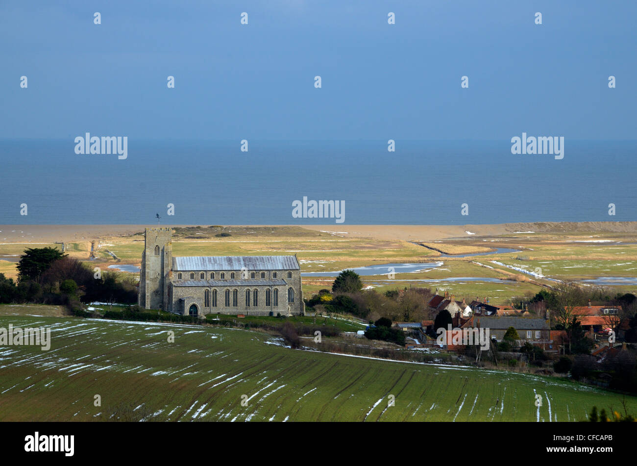 View of Salthouse village showing the Church of St Nicholas, grazing marshes and shingle bank, Norfolk Stock Photo