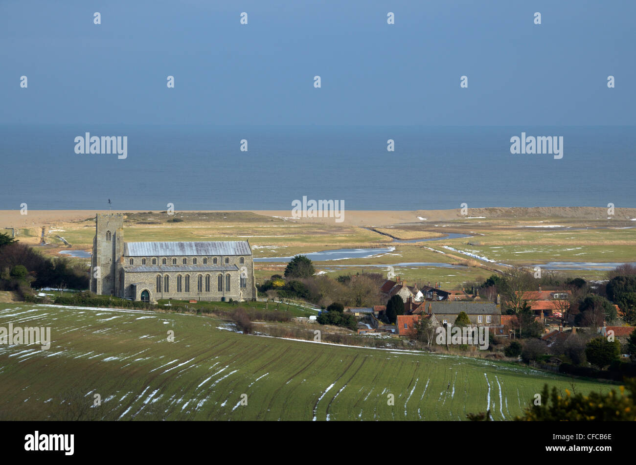 View of Salthouse village showing the Church of St Nicholas, grazing marshes and shingle bank, Norfolk Stock Photo