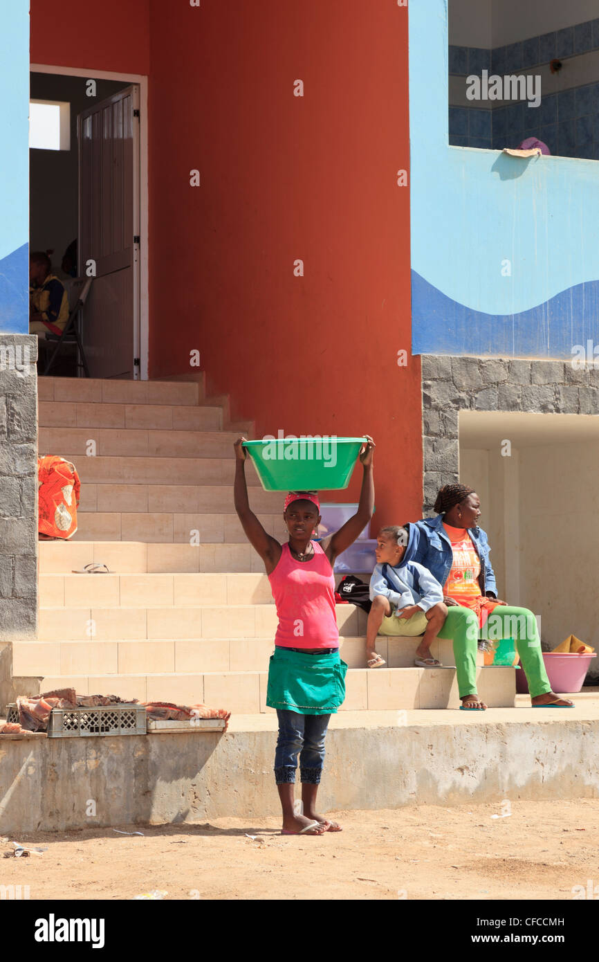 Sal Rei, Boa Vista, Cape Verde. Scene outside new municipal fish market with local woman carrying a bowl of fish on her head Stock Photo