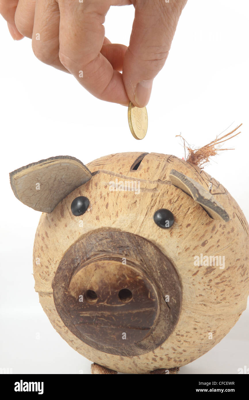 Saving, male hand putting a coin into piggy bank Stock Photo - Alamy