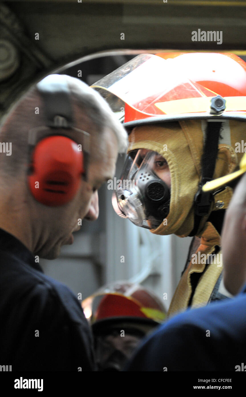 A sailor, wearing fire fighting equipment listens to an inspector during a main space fire drill aboard the amphibious assault ship USS Kearsarge (LHD 3). Kearsarge is underway, completing Afloat Training Group 1.3 basic phase training. Stock Photo