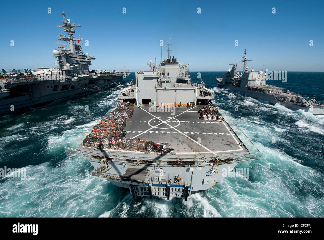 The Military Sealift Command fast combat support ship USNS Bridge (T-AOE 10) prepares to conduct a replenishment at sea with the Nimitz-class aircraft carrier USS Carl Vinson (CVN 70), left, and the Ticonderoga-class guided missile cruiser USS Bunker Hill (CG 52) (CG 52). Carl Vinson and Carrier Air Wing (CVW) 17 are deployed to the U.S. 5th Fleet area of responsibility. Stock Photo