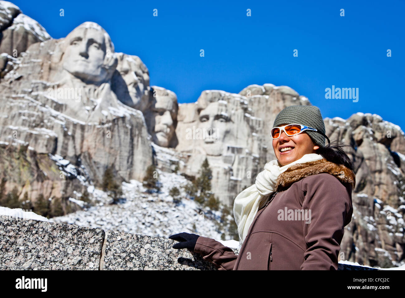a thirty year old, Japanese-American woman stands in front of Mt Rushmore National Memorial. Stock Photo