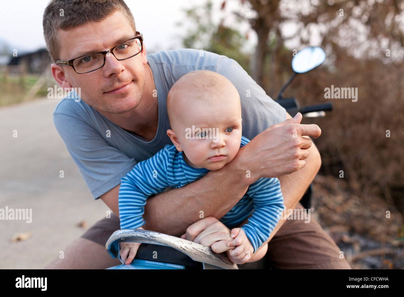 Father and son sitting on a moped, Pai, Thailand, Asia Stock Photo