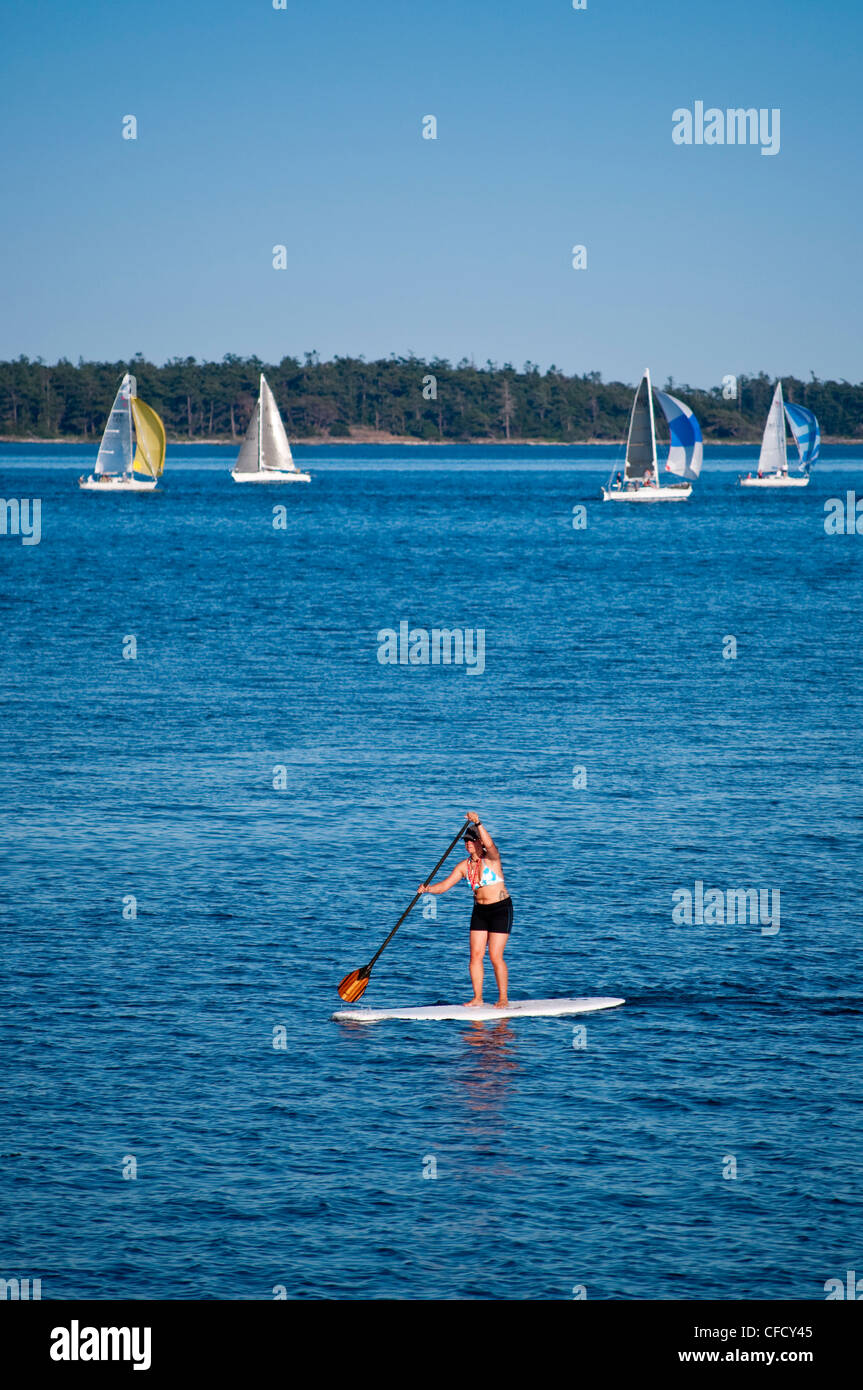 Paddleboarder and Sailboats with spinnakers from Royal Victoria Yacht Club, Victoria, British Columbia, Canada Stock Photo