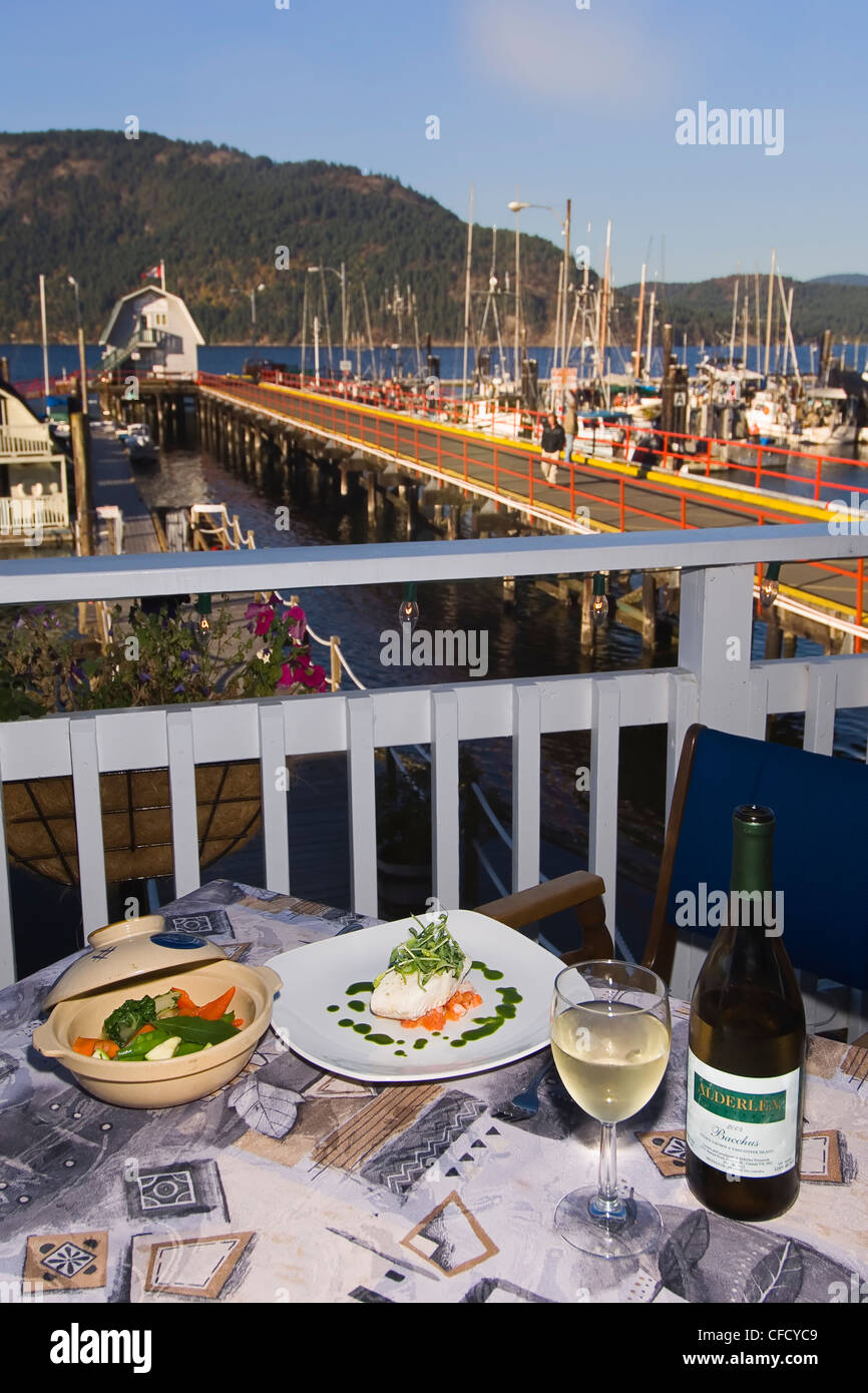 Masthead Restaurant gourmet halibut dish and local VQA wine on terrace of restaurant overlooking Cowichan Bay. Stock Photo