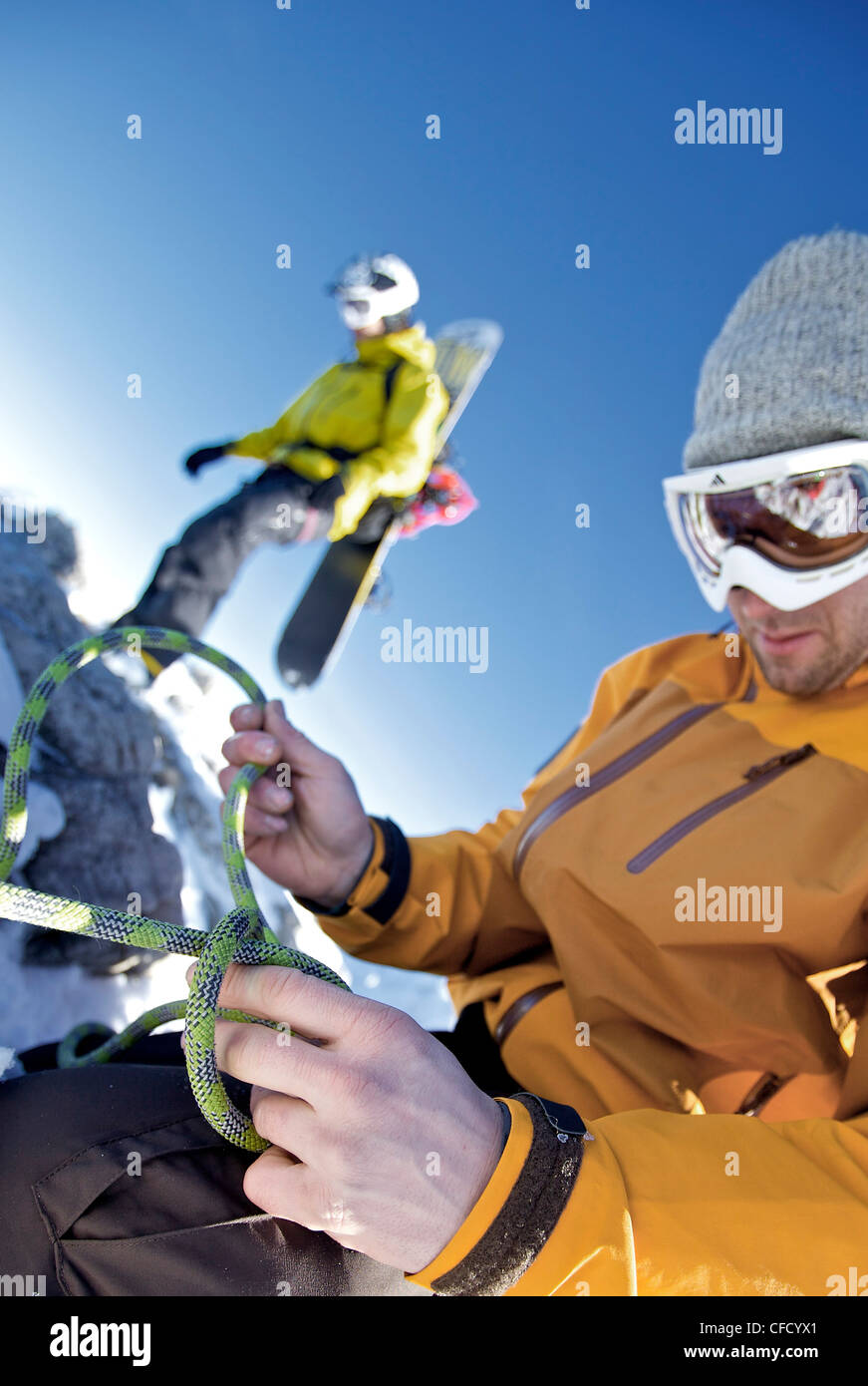 Snowboarder preparing a climbing rope, Oberjoch, Bad Hindelang, Bavaria, Germany Stock Photo
