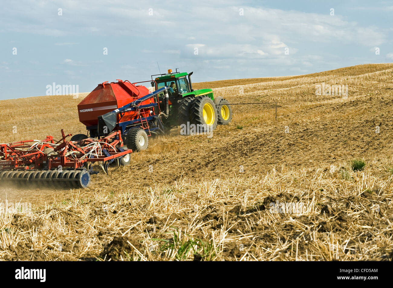Moving tractor and air till seeder planting canola in a zero till wheat
