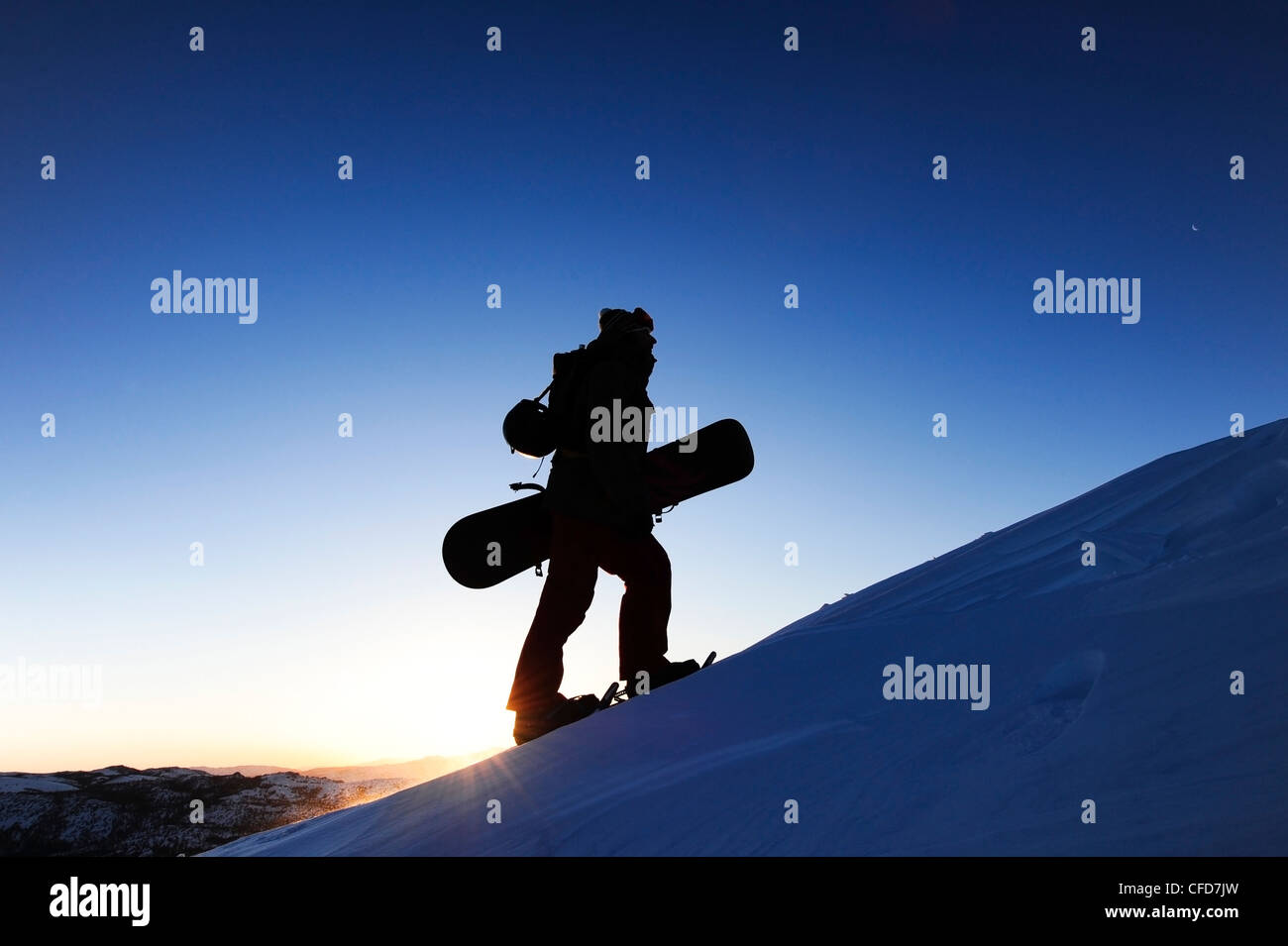 A silhouette of a snowboarder snowshoeing at sunrise in the Sierra Nevada near Lake Tahoe, California. Stock Photo