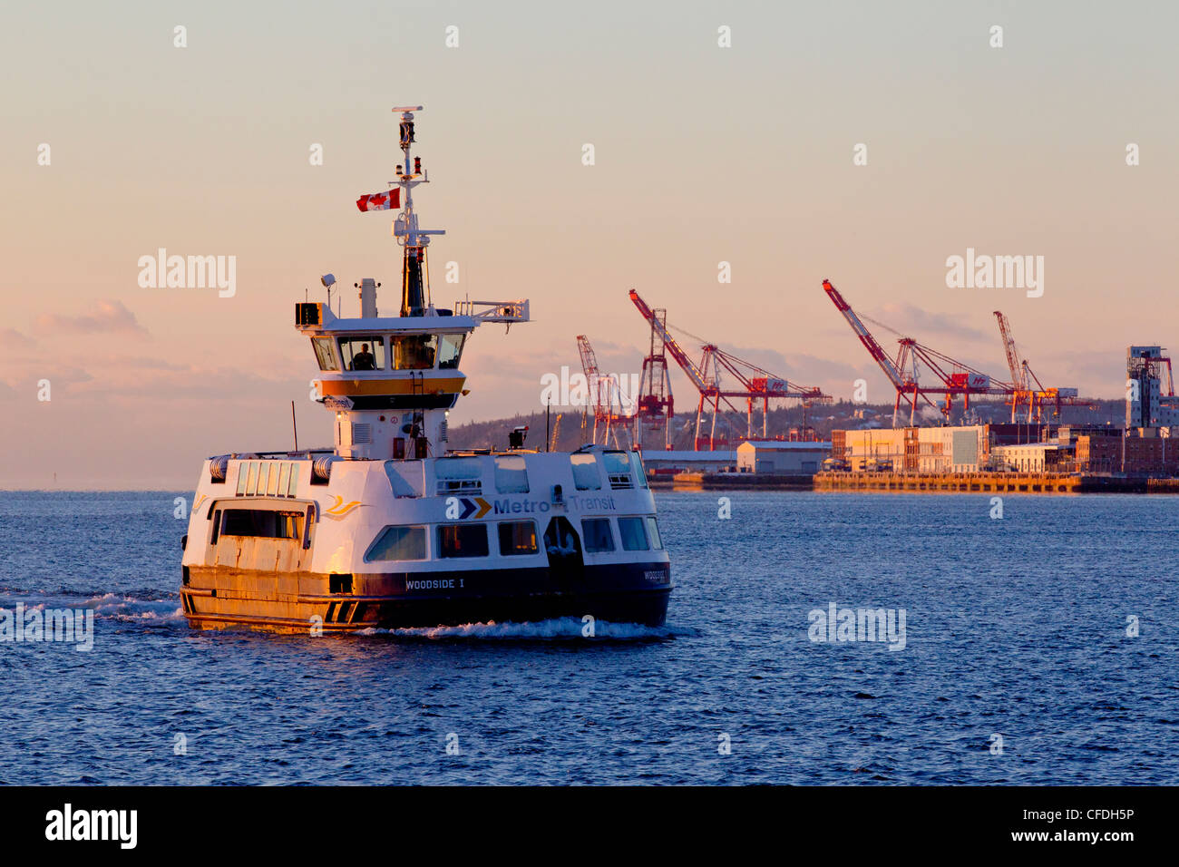 Passenger ferry passing in front of container port at dawn in winter, Halifax, Nova Scotia, Canada Stock Photo