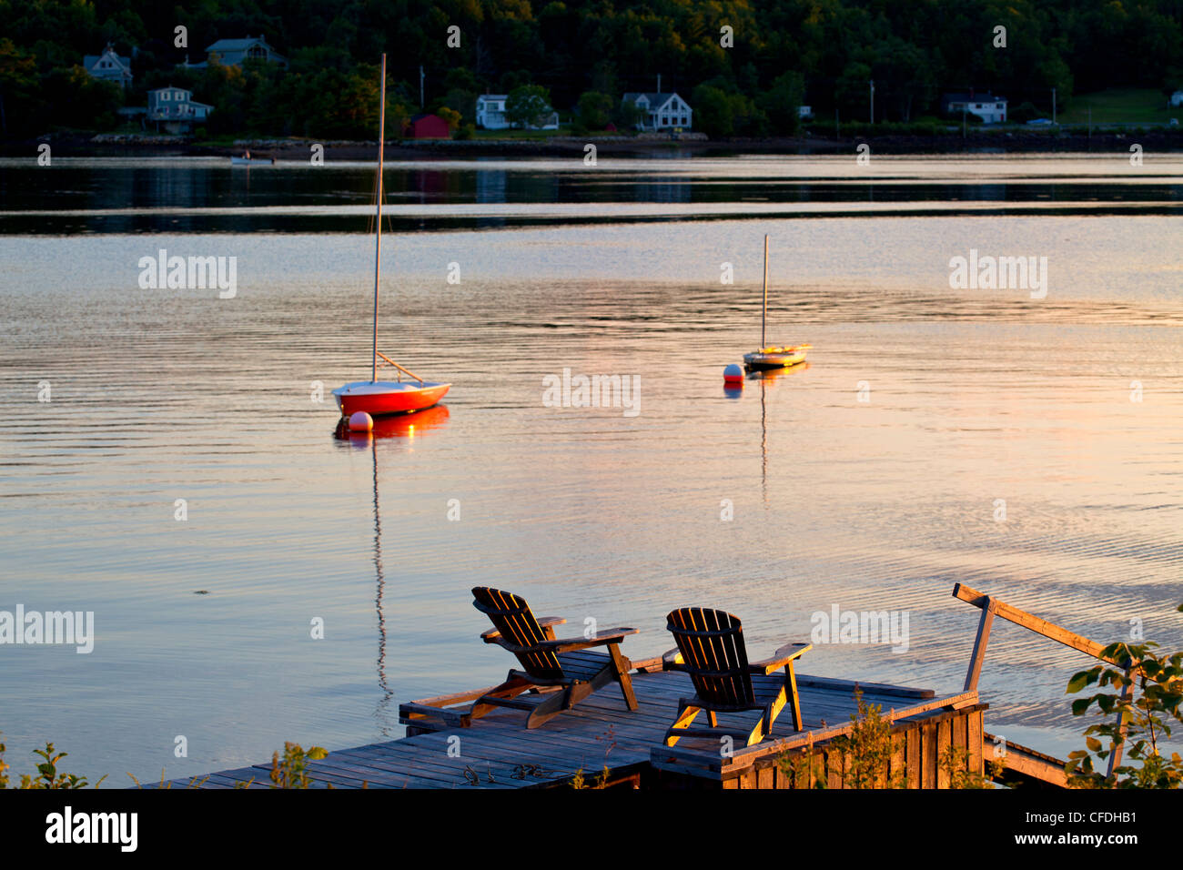 Lawn chairs on wharf and sailboats in sunset, LaHave River, Nova Scotia, Canada Stock Photo