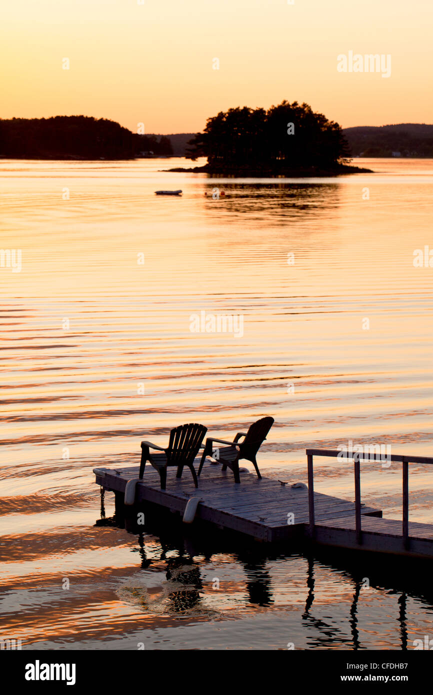 Lawn chairs on wharf at sunset, LaHave River, Nova Scotia, Canada Stock Photo