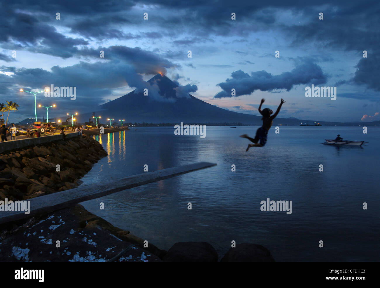 Boy jumping into the sea before a glowing Mayon Volcano, Legazpi City, Luzon Island, Philippines, Asia Stock Photo
