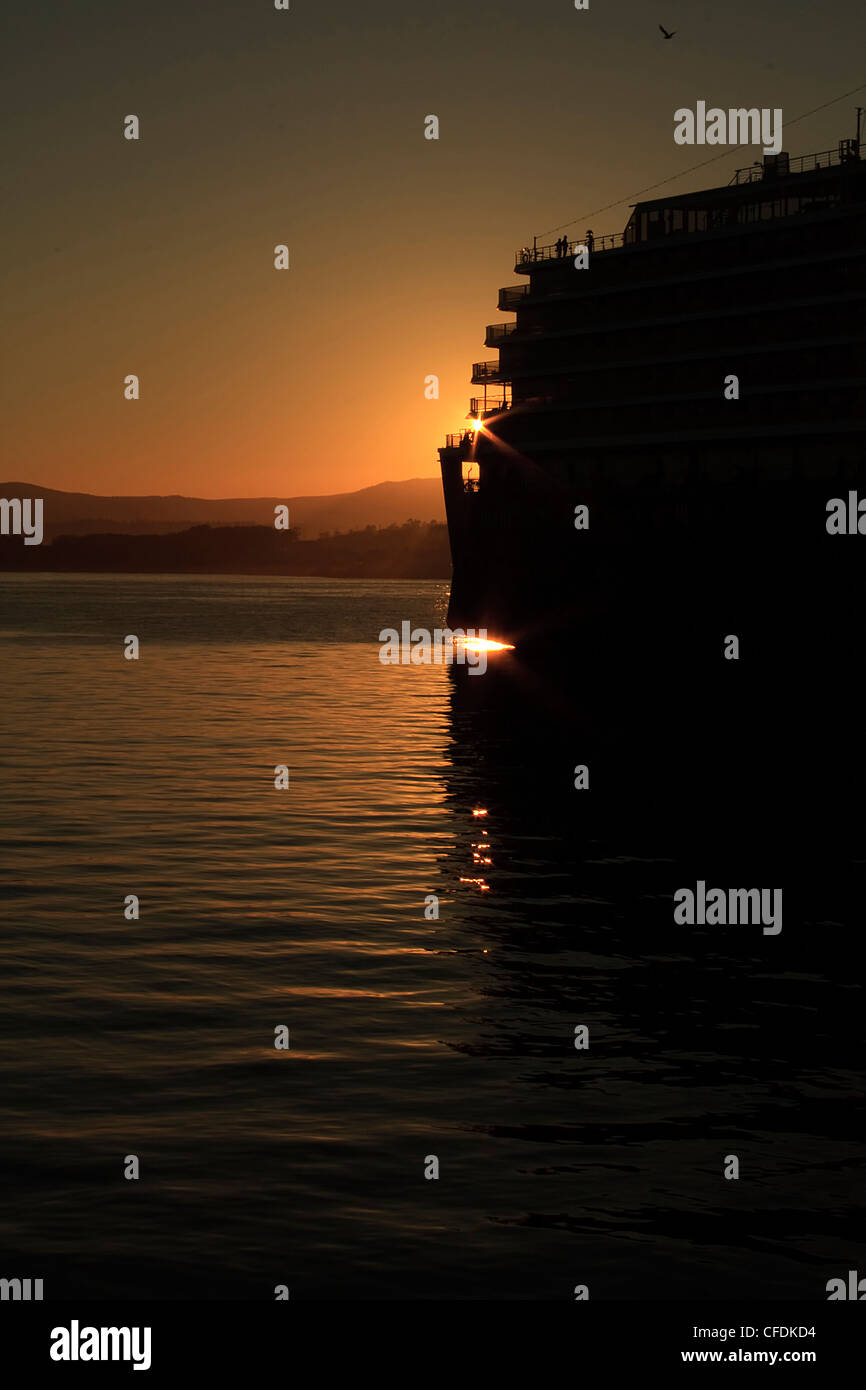 The sun sets behind a cruise ship docked at Ogden Point, Victoria, British Columbia, Canada. Stock Photo