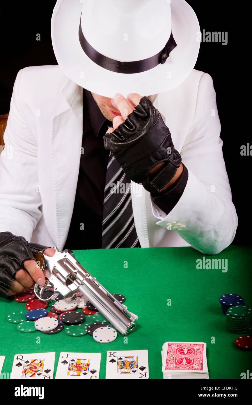 View of a gangster man playing some cards and poker, holding a gun