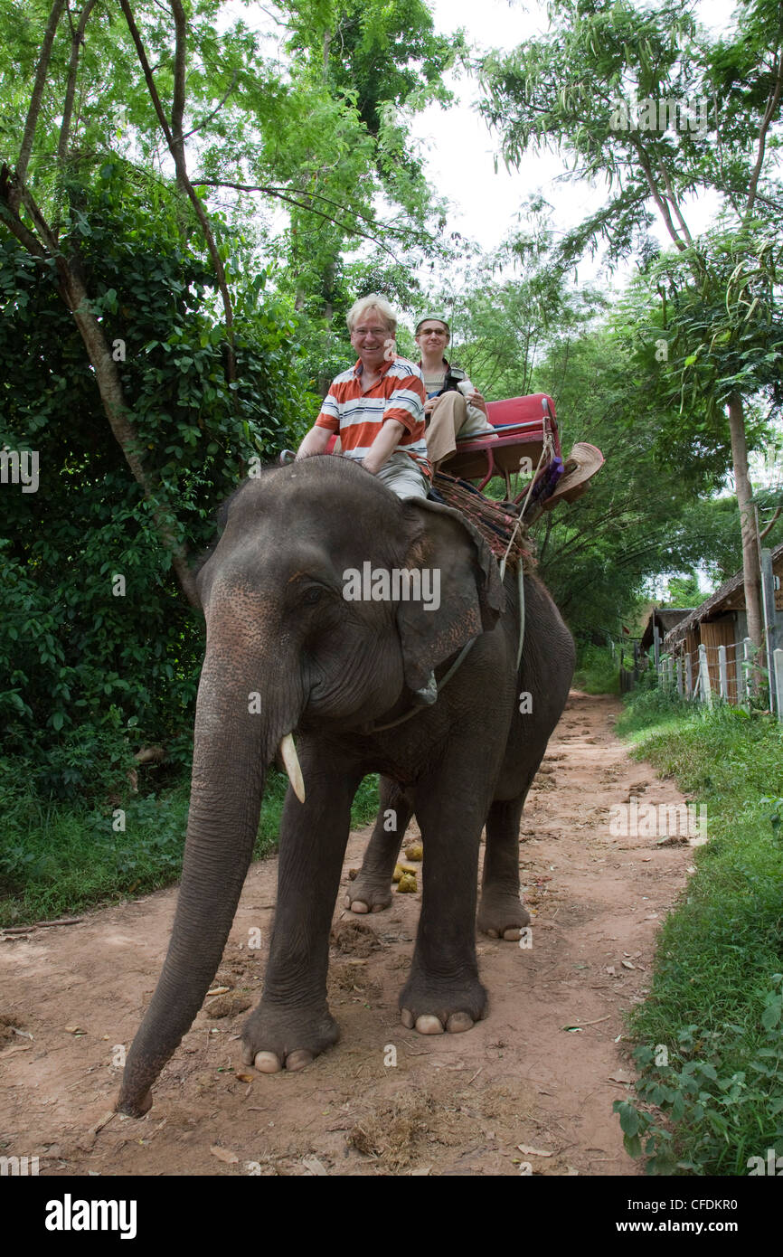Tourists ride elephants at Sai Yok Elephant Village [MR], near Kanchanaburi, Thailand Stock Photo