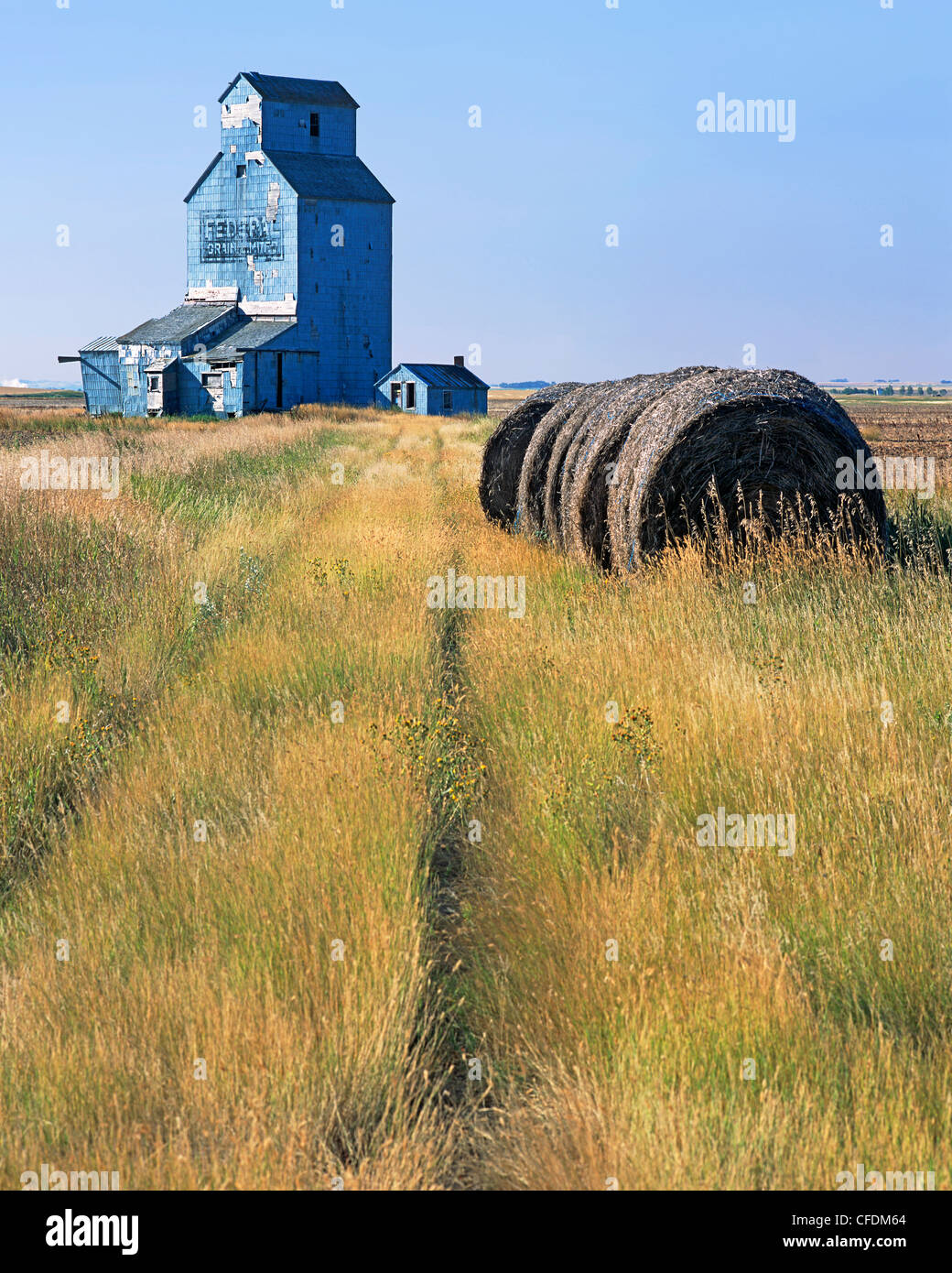 Old grain elevator and hay bales, Moreland, Saskatchewan, Canada Stock Photo