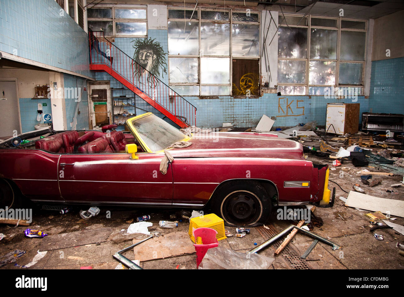 A Cadillac sits vandalized in a derelict warehouse inhabited by vagrants in seven sisters, Tottenham, London. Stock Photo