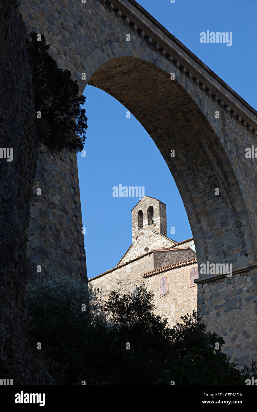Church seen through arch of ancient bridge at Minerve, a Cathar Languedoc village, Herault, France Stock Photo
