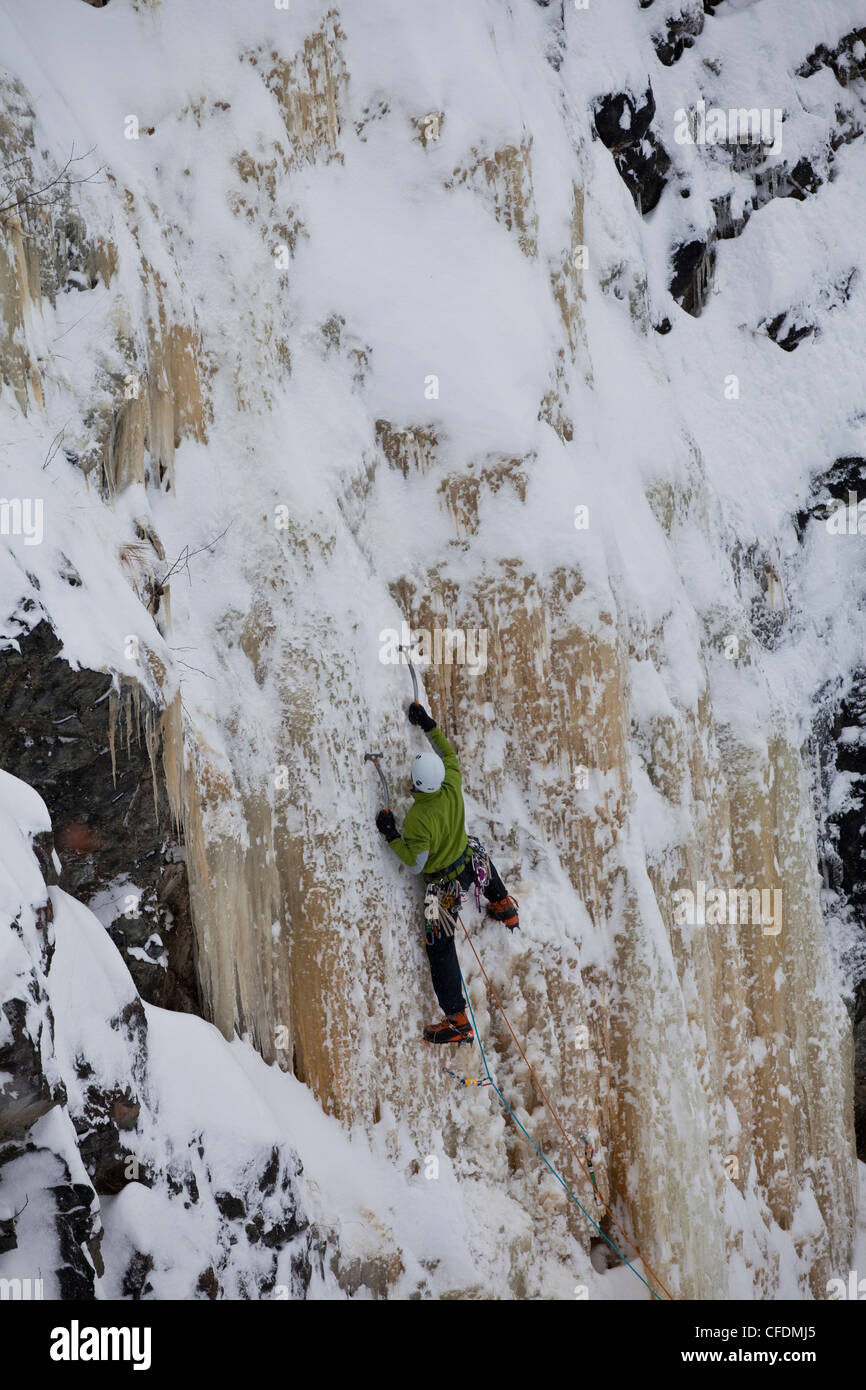 A young man ice climbing some grade 4 ice outside of Sherbrooke, Quebec, Canada Stock Photo