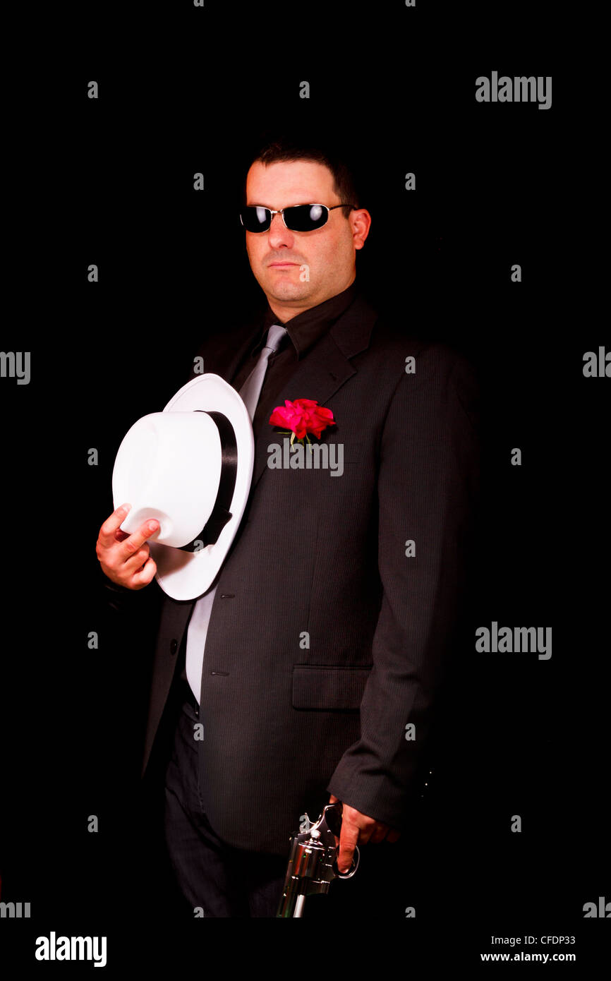 View of a dark suit gangster man holding a gun Stock Photo - Alamy