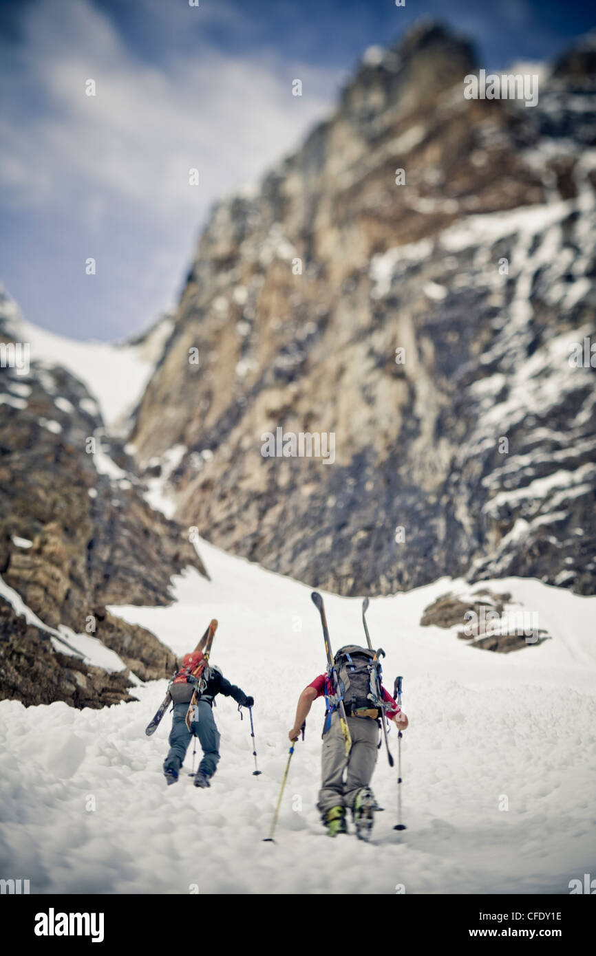 Two male backcountry skiers bootpack up a steep spring couloir. 3/4 couloir, Moraine Lake, Banff National Park, Alberta, Canada Stock Photo