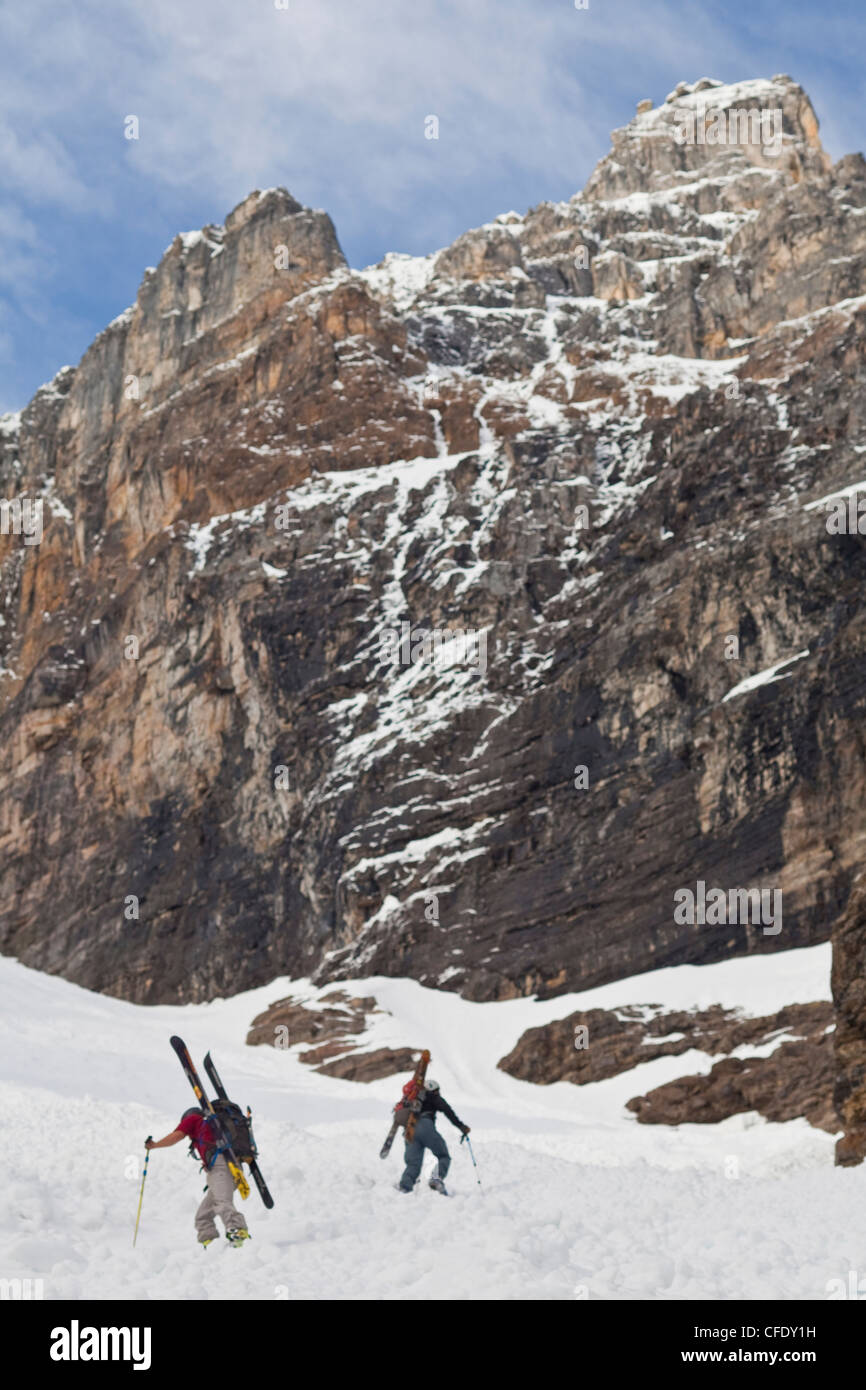 Two male backcountry skiers bootpack up a steep spring couloir. 3/4 couloir, Moraine Lake, Banff National Park, Alberta, Canada Stock Photo