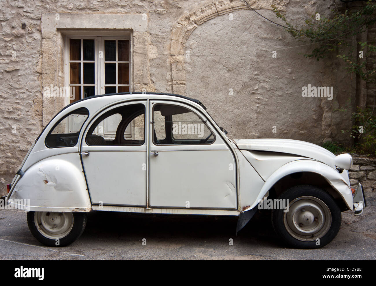 A slightly dented white Citroën 2CV parked in a quiet village in Provence, France (Saignon). Stock Photo