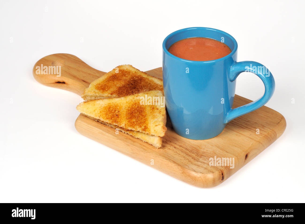 A cup of tomato soup with toast on deli board on white background cut out. Stock Photo