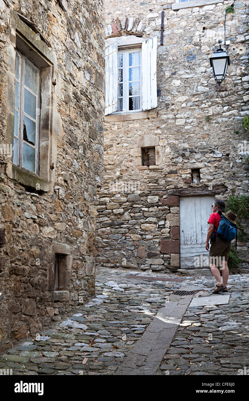 Woman backpacker in back street of Brusque, Aveyron, France Stock Photo