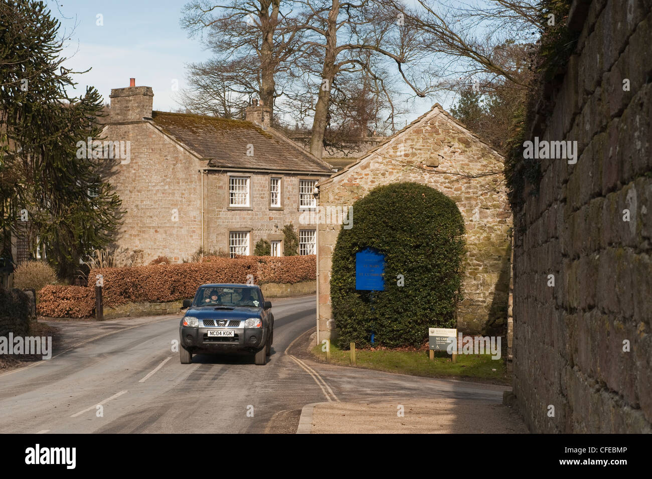 Front view of Nissan pick-up-truck traveling or being driven on country road past quaint cottage - Bolton Abbey village, North Yorkshire, England, UK. Stock Photo