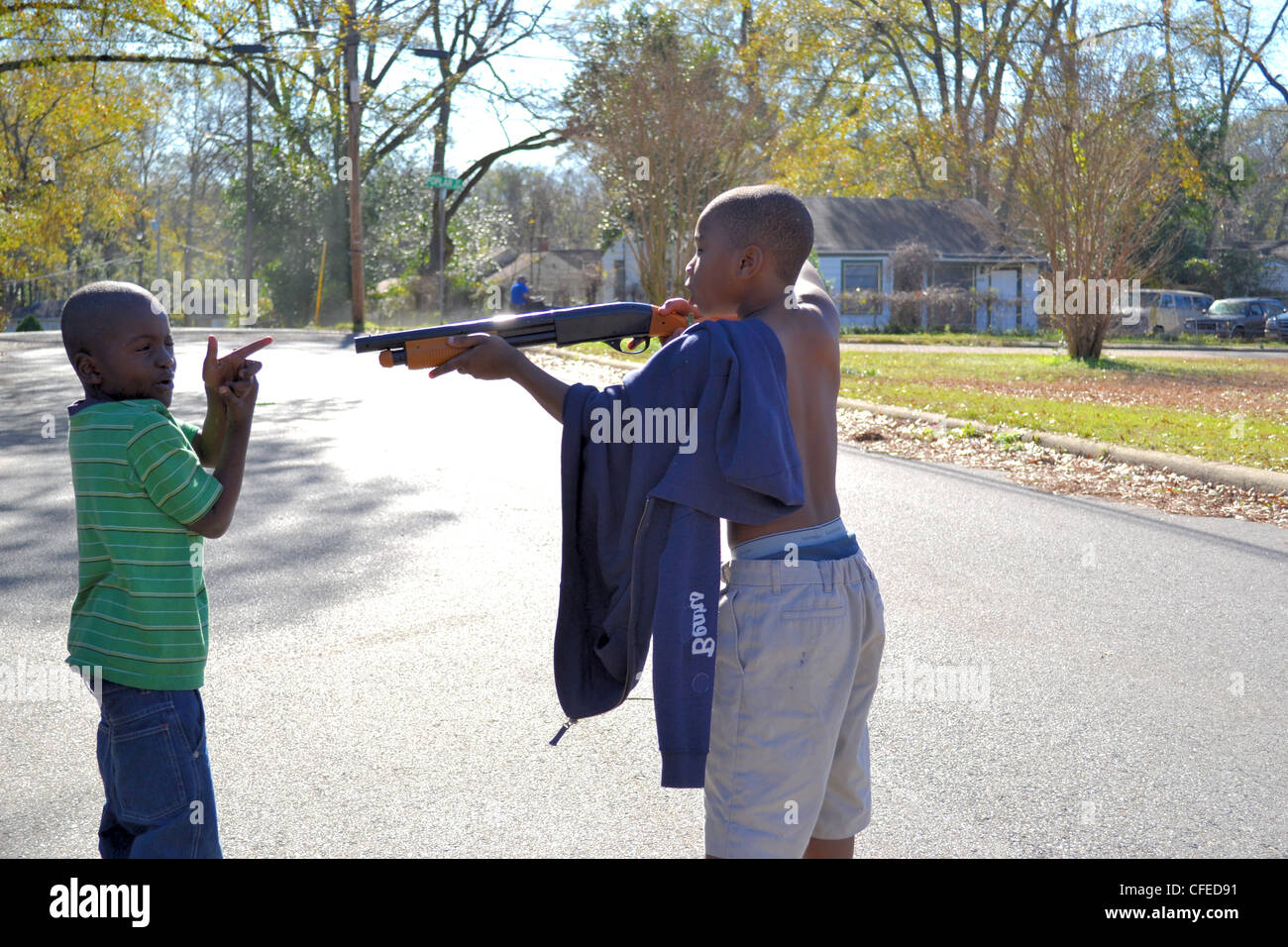 Teenager points a toy rifle at a young friend. Rifle was a Christmas present. American south. Stock Photo