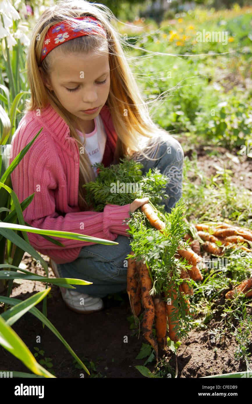 Girl in vegetable garden hold carrots Stock Photo