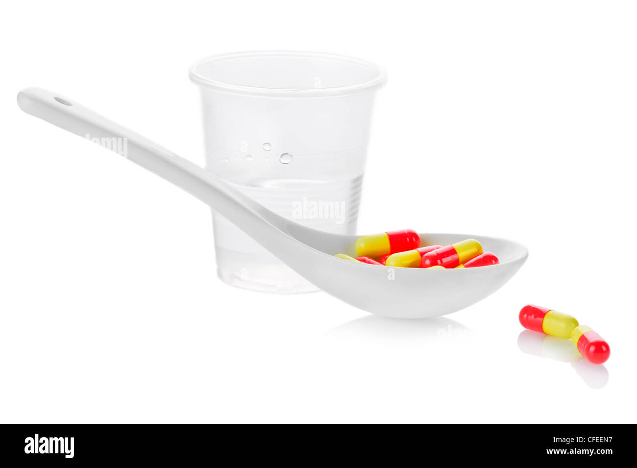 Pharmacy. Antibiotic pills in spoon and plastic glass of water on white background Stock Photo
