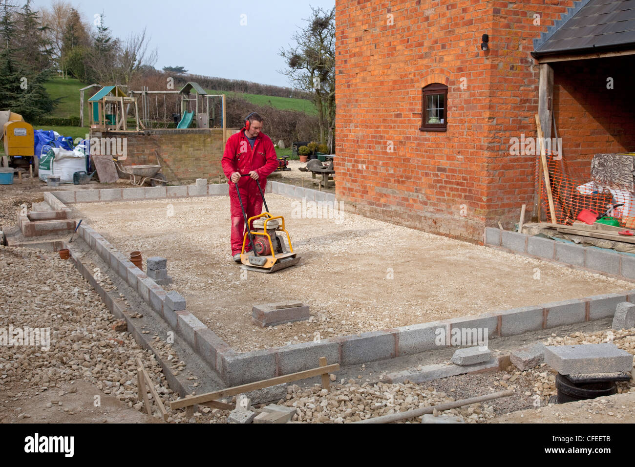 Builder compacting foundations with portable vibrator compactor Colemans Hill Cottage Mickleton Chipping Campden UK Stock Photo