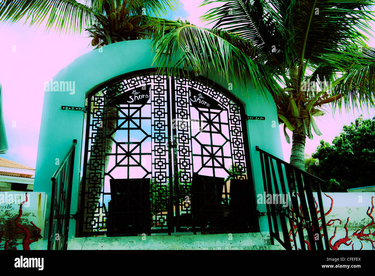 Neon green and pink colors on restaurant iron gate Grand Cast Saint Martin with tropical palm trees Stock Photo