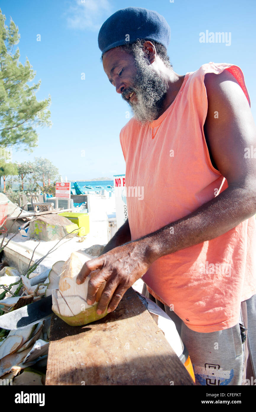 Smiling, bearded, black man wearing a hat selling coconuts on Orient