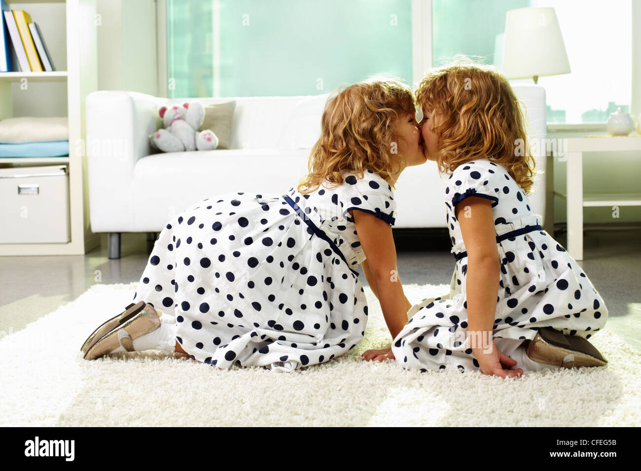 Portrait of happy twin girls kissing at home Stock Photo Alamy