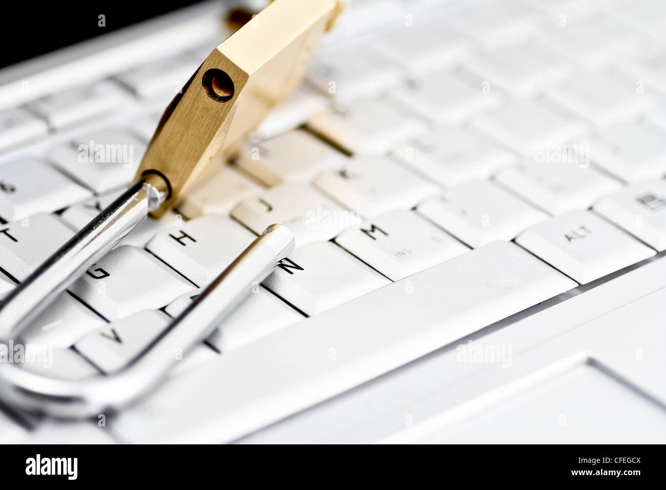 Brass padlock in unlocked position on top of computer keyboard Stock Photo