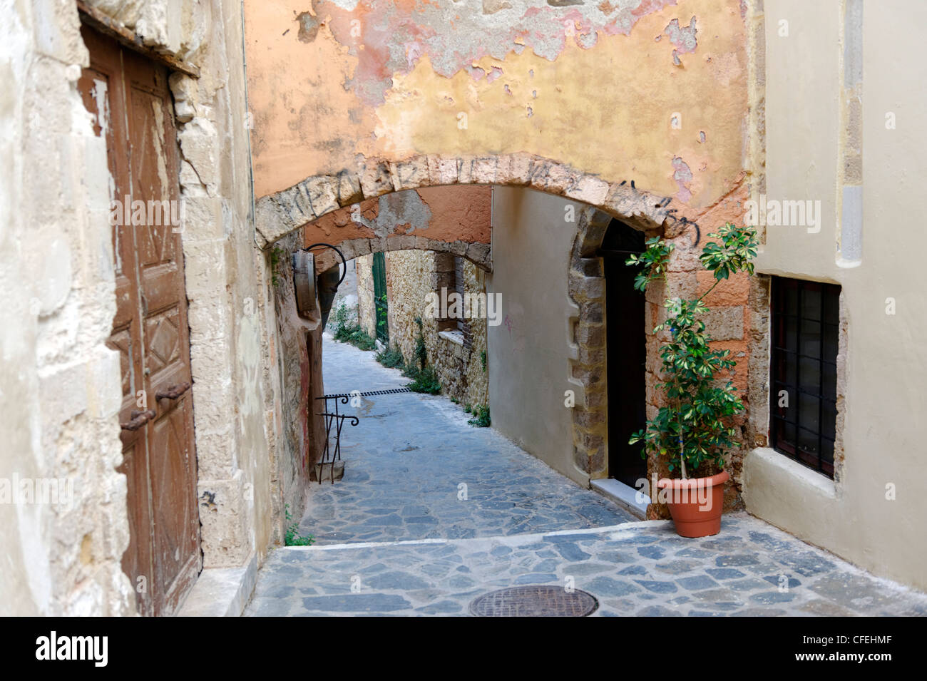 A stoned tiled winding alleyway lined with colourful pot plants, overhanging balconies and ornate doorways. Stock Photo