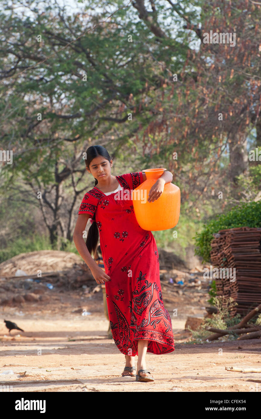 Rural Indian village teenage girl carrying a water pot home. Andhra