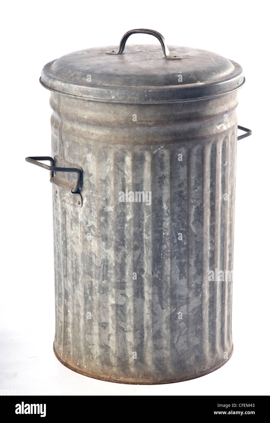 An old corrugated metal garbage bin with folding handles and lid. Stock Photo
