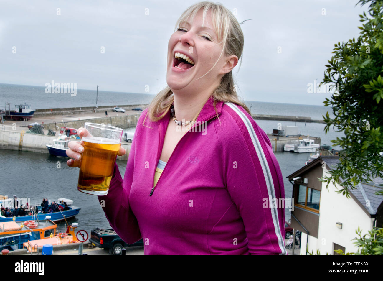 Twenty something girl enjoying herself drinking a pint of lager Stock Photo