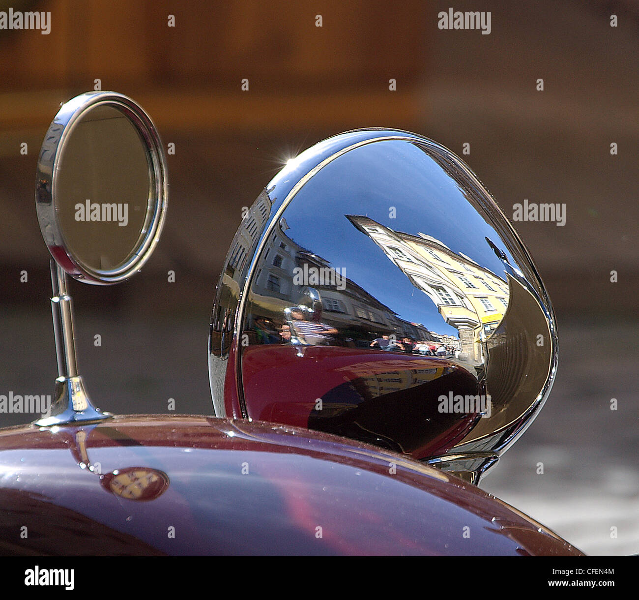 Distorted reflection of a an old town square in Summer in the chromed headlight of a vintage car. Double reflection of the image Stock Photo