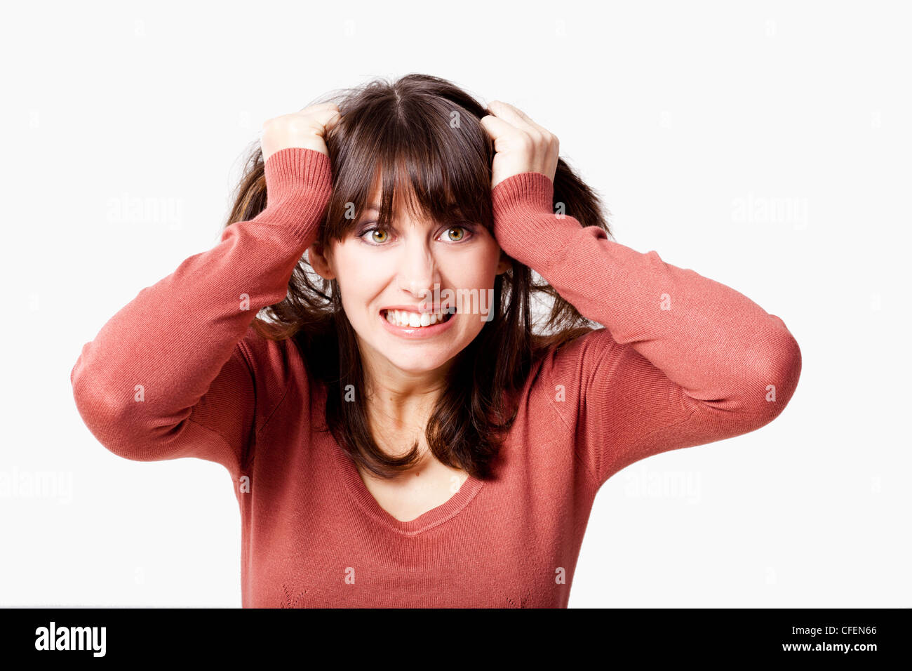 Portrait of a stressed young woman pulling her hair out, isolated over a gray background Stock Photo