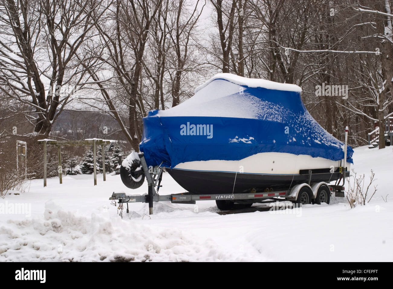 A motorboat waits for warmer weather in the yard of a New England home. Stock Photo