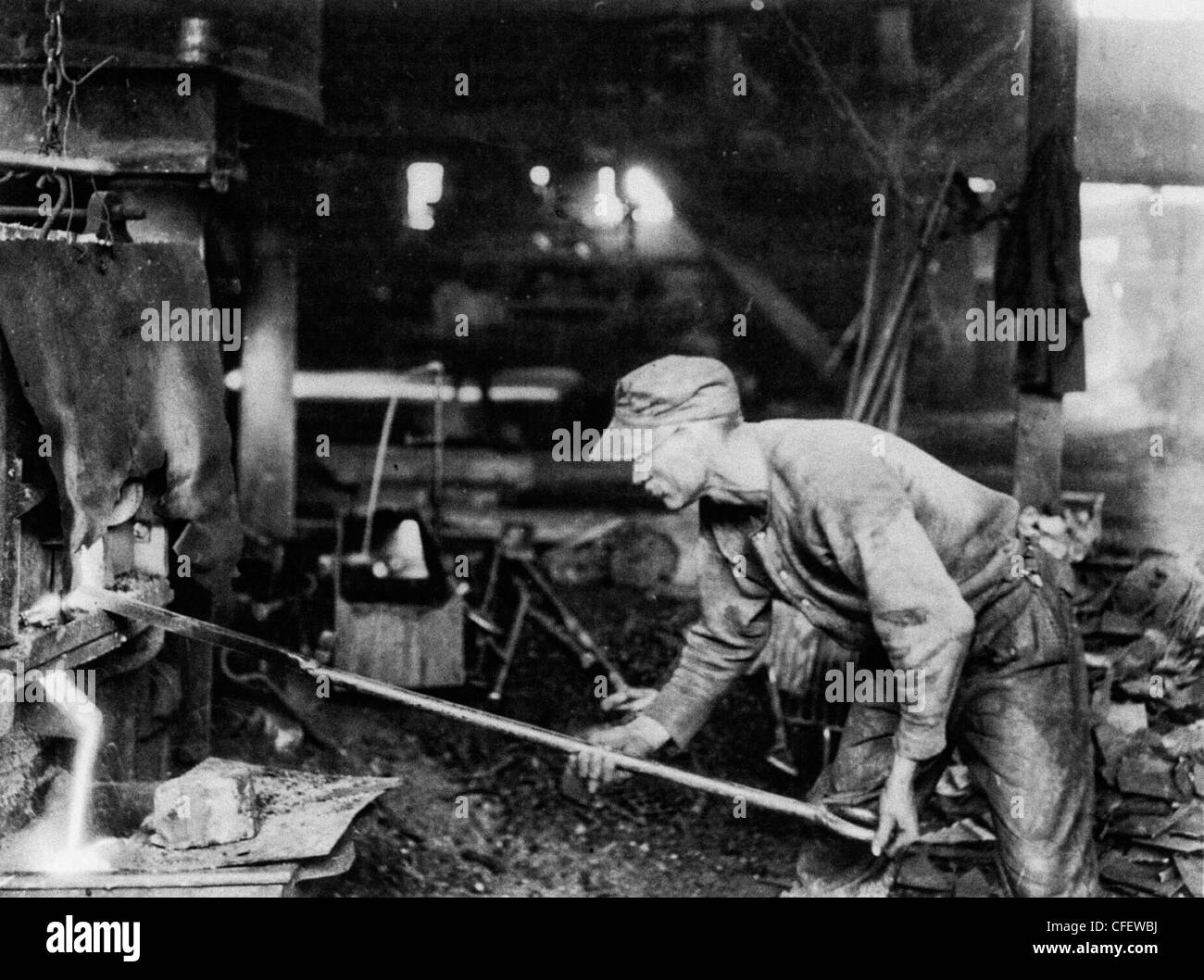 The threatening big steel strike. A view of one of the strikers who is asking for more pay, at his work of puddling, where he is 'working up' his 'ball of iron' to be carried to the 'squeezer', circa 1919 Stock Photo