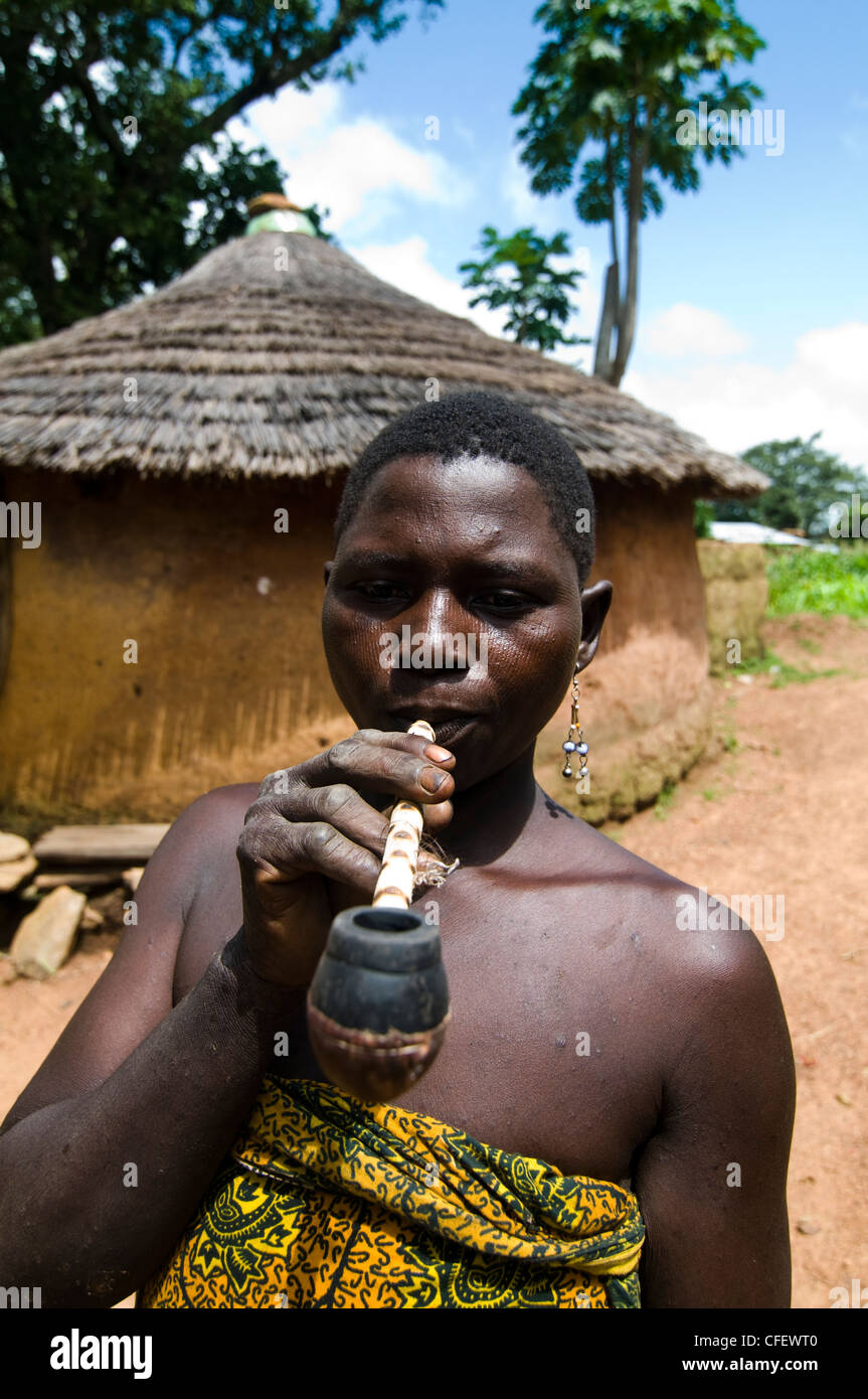 A Somba / Betamaribé  woman smoking a traditional pipe in her village. Stock Photo