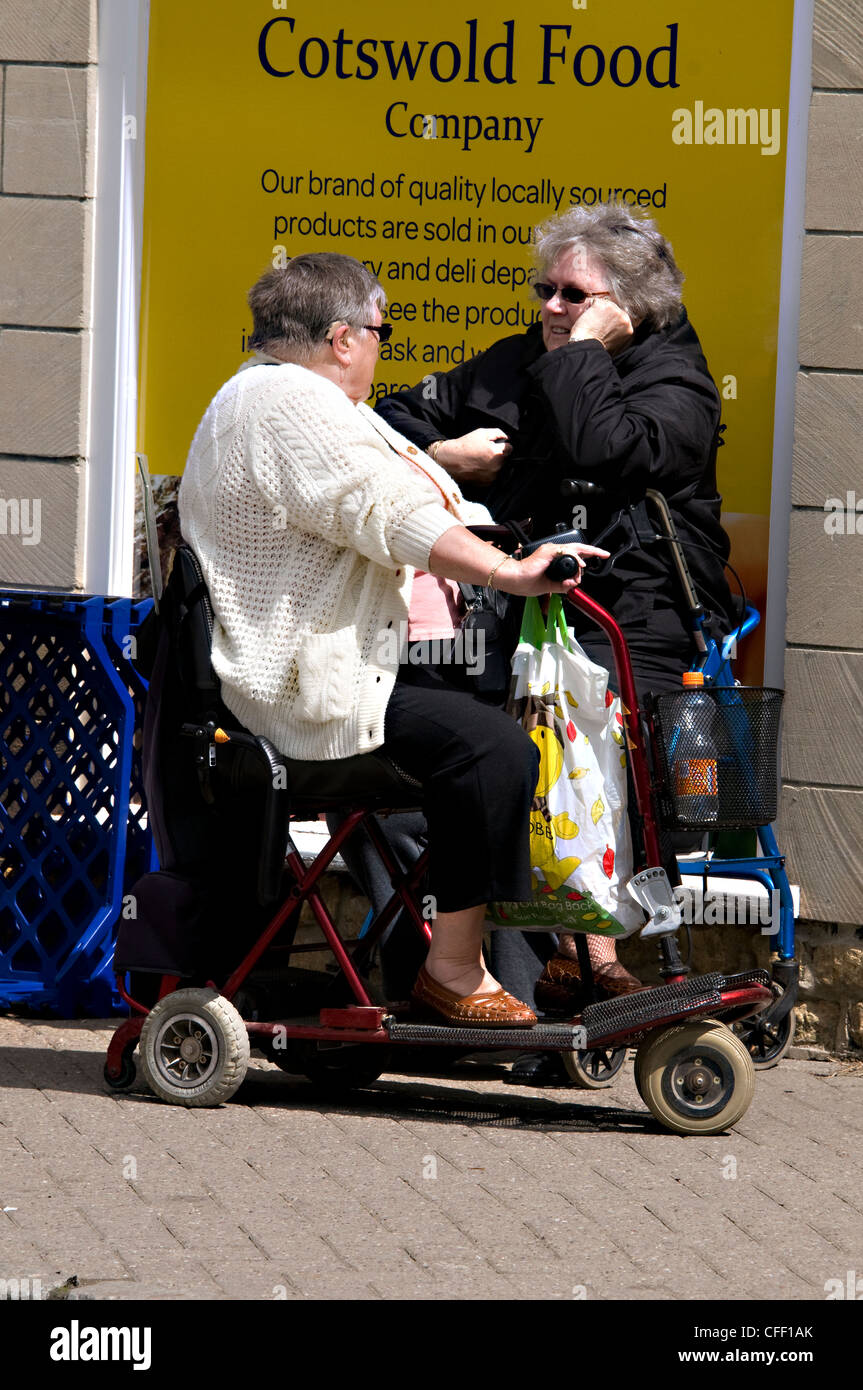 Two disabled shoppers stop for a chat in a village in Britain Stock Photo