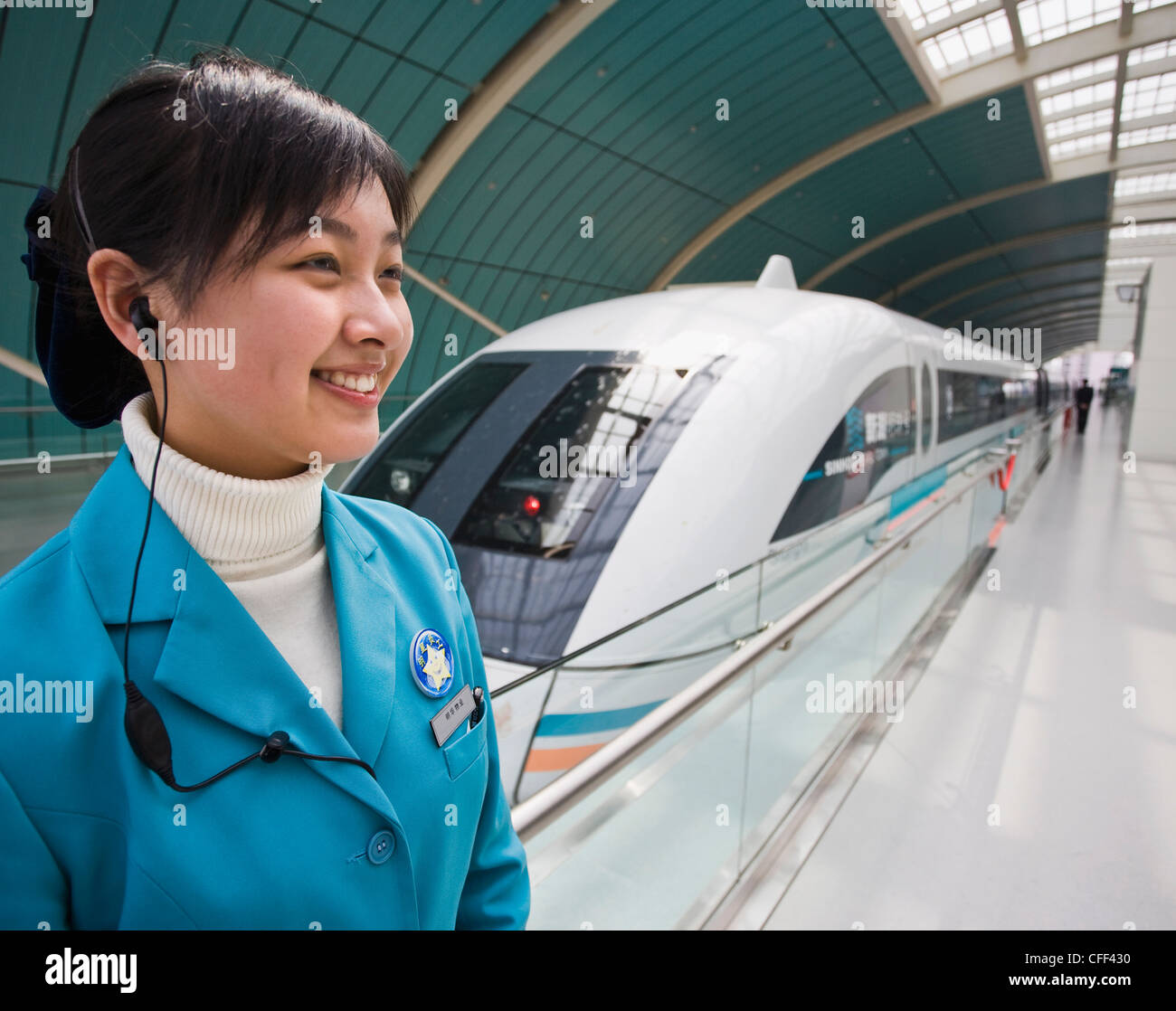 A female attendant standing next to a Magnetic Levitation train on railway platform in Shanghai, China Stock Photo
